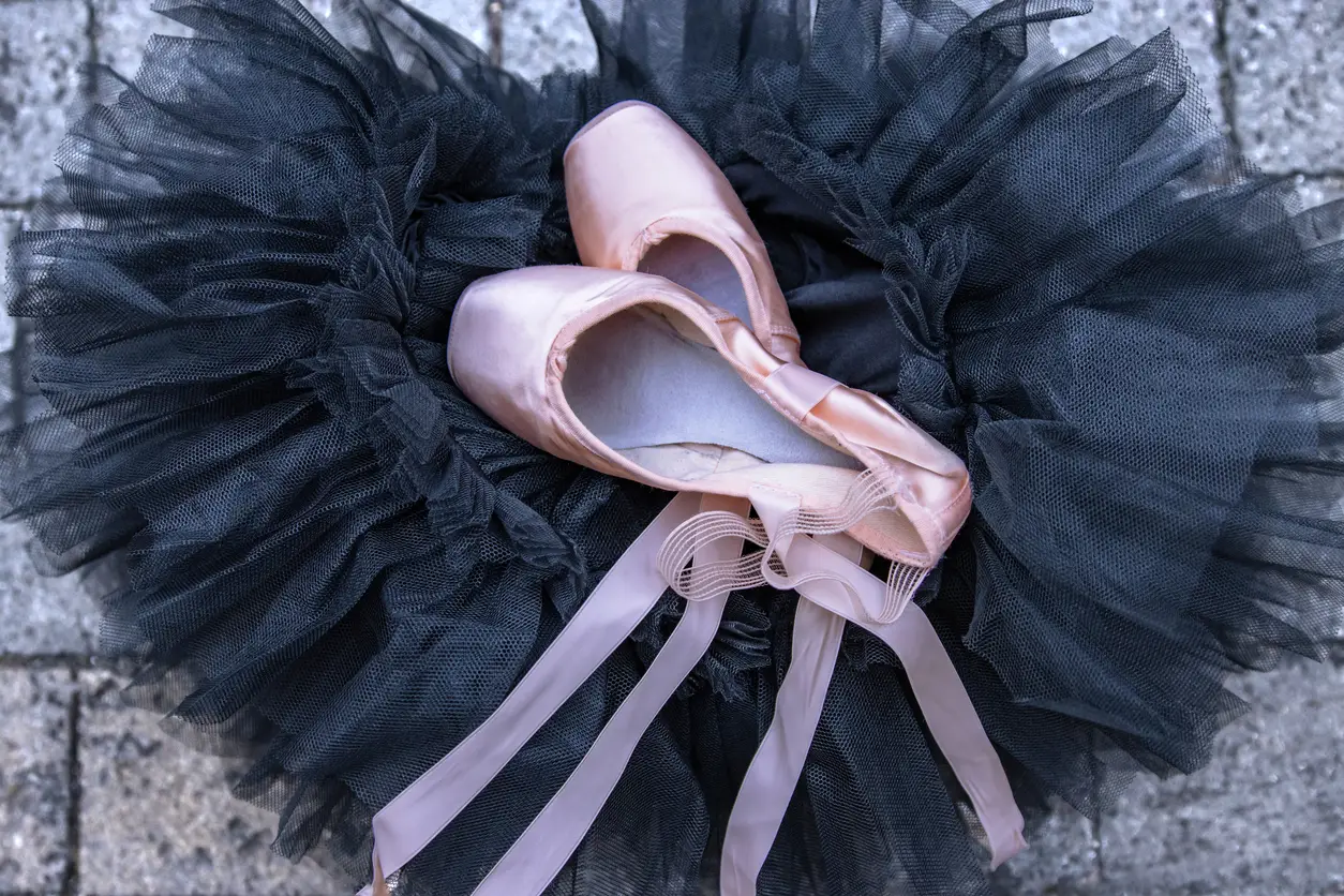 Pink pointe shoes placed on a black tutu. Classic ballet dancer accessories